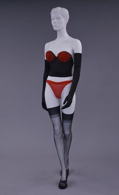 Black and rosebud corset by Dominique with red thong paired with black satin evening gloves by Satin Loves, and black nylon thigh-high stockings and heels by Esprit worn by Debbie Sundahl/Fanny Fatale ca. 1984  